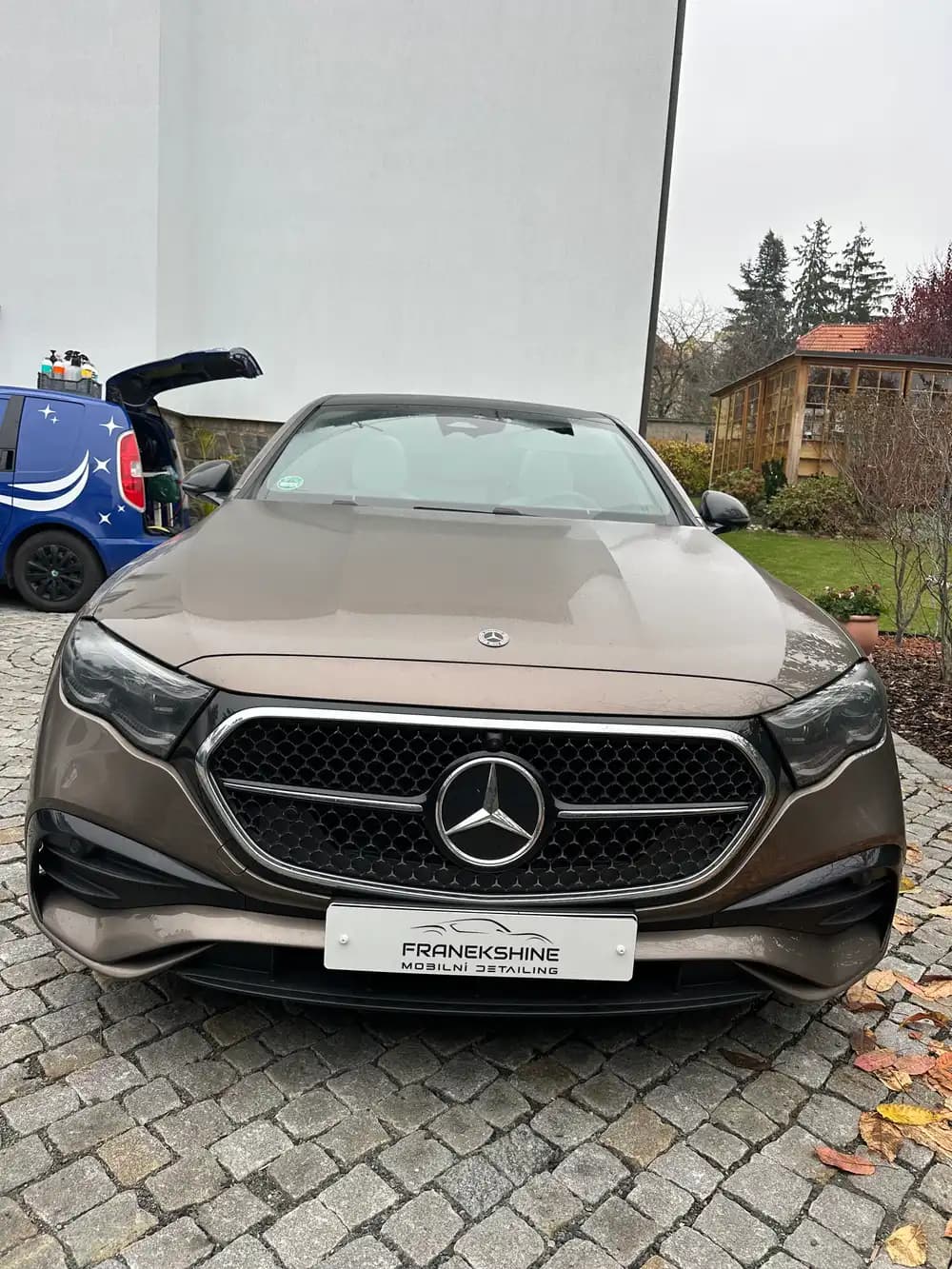 Hnědý Mercedes kabriolet zepředu v zahradě u skleníku