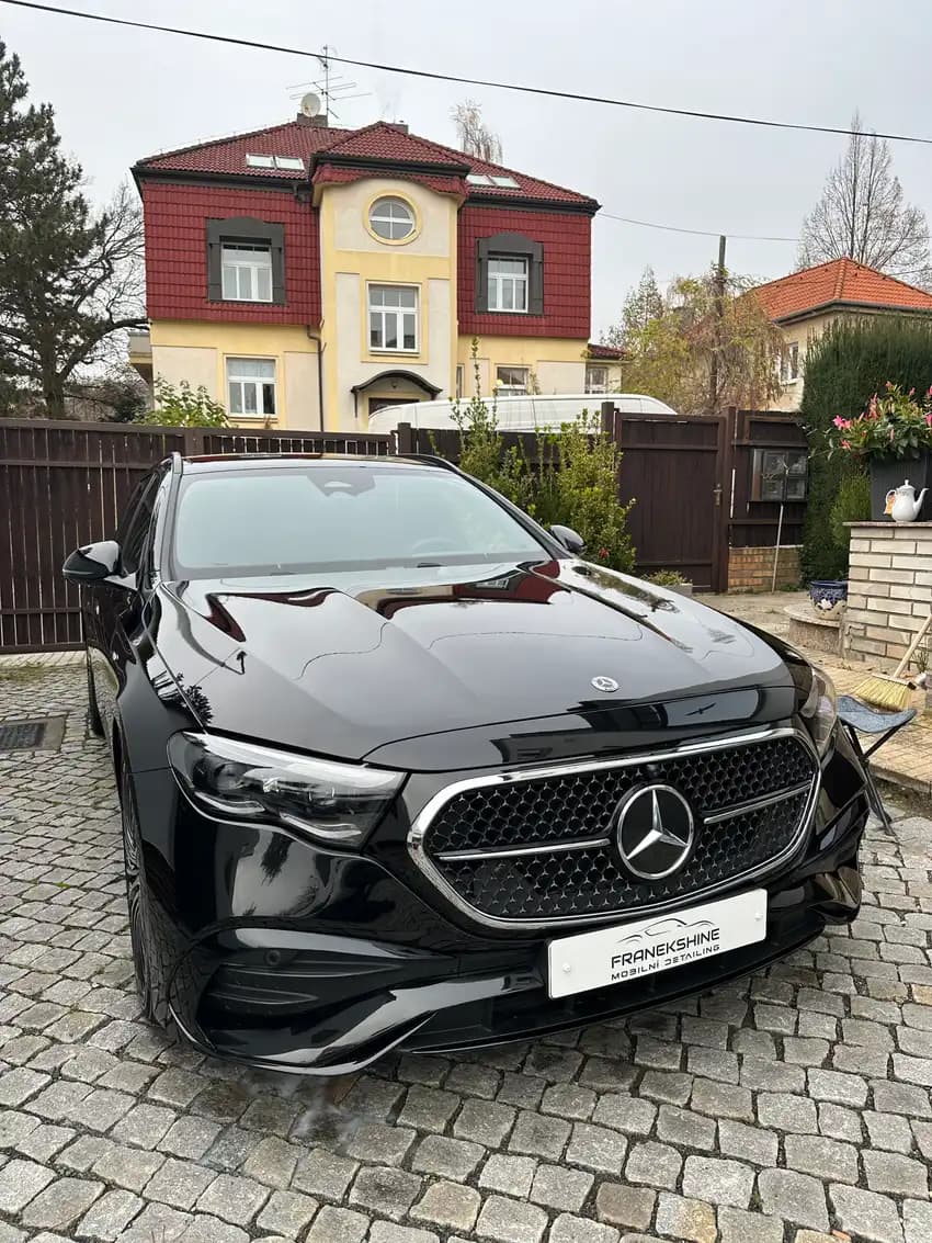 Detail masky černého Mercedesu s kapkami vody po opláchnutí