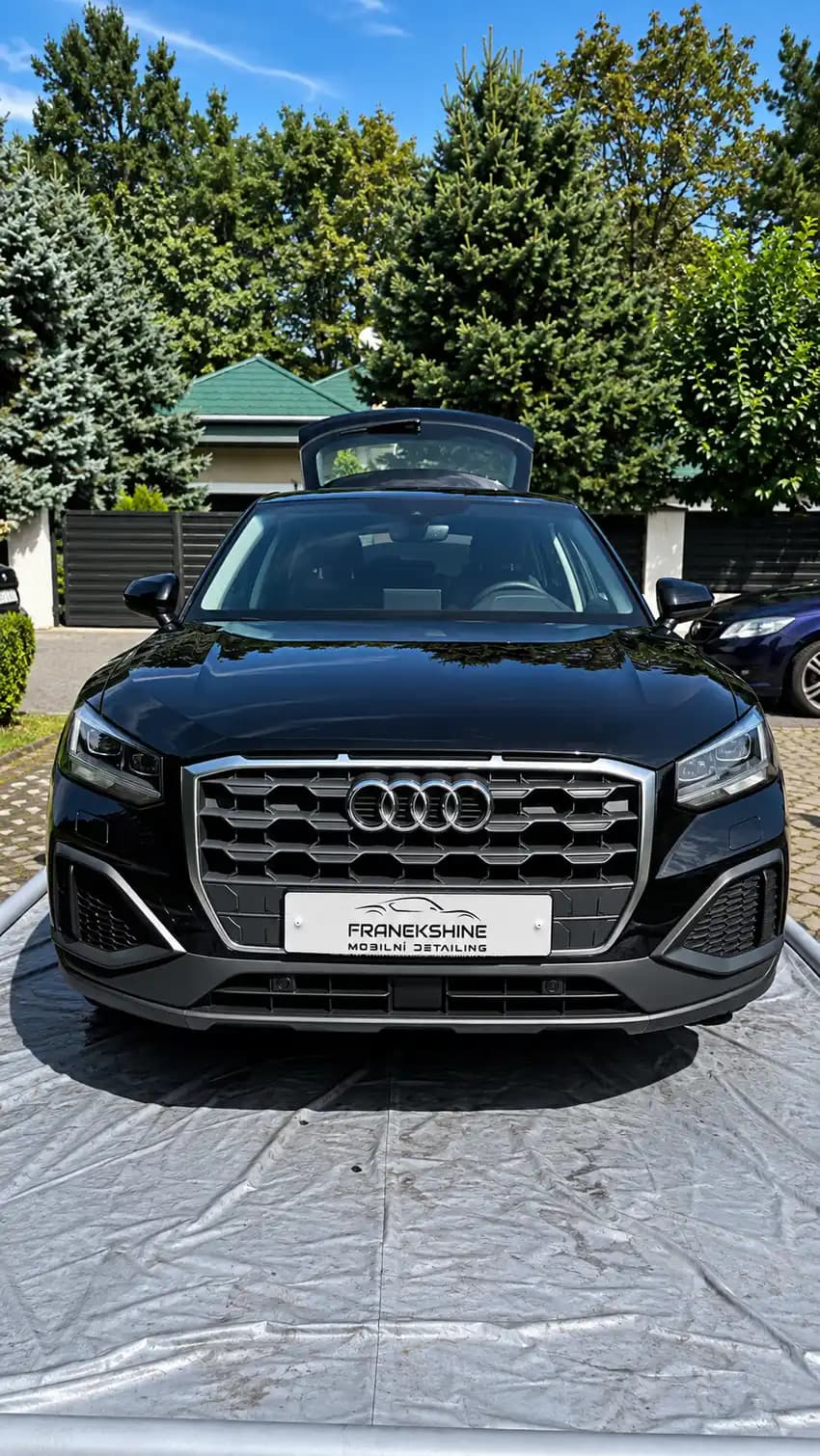 Černé Audi Q2 zepředu s otevřeným kufrem na ochranné plachtě