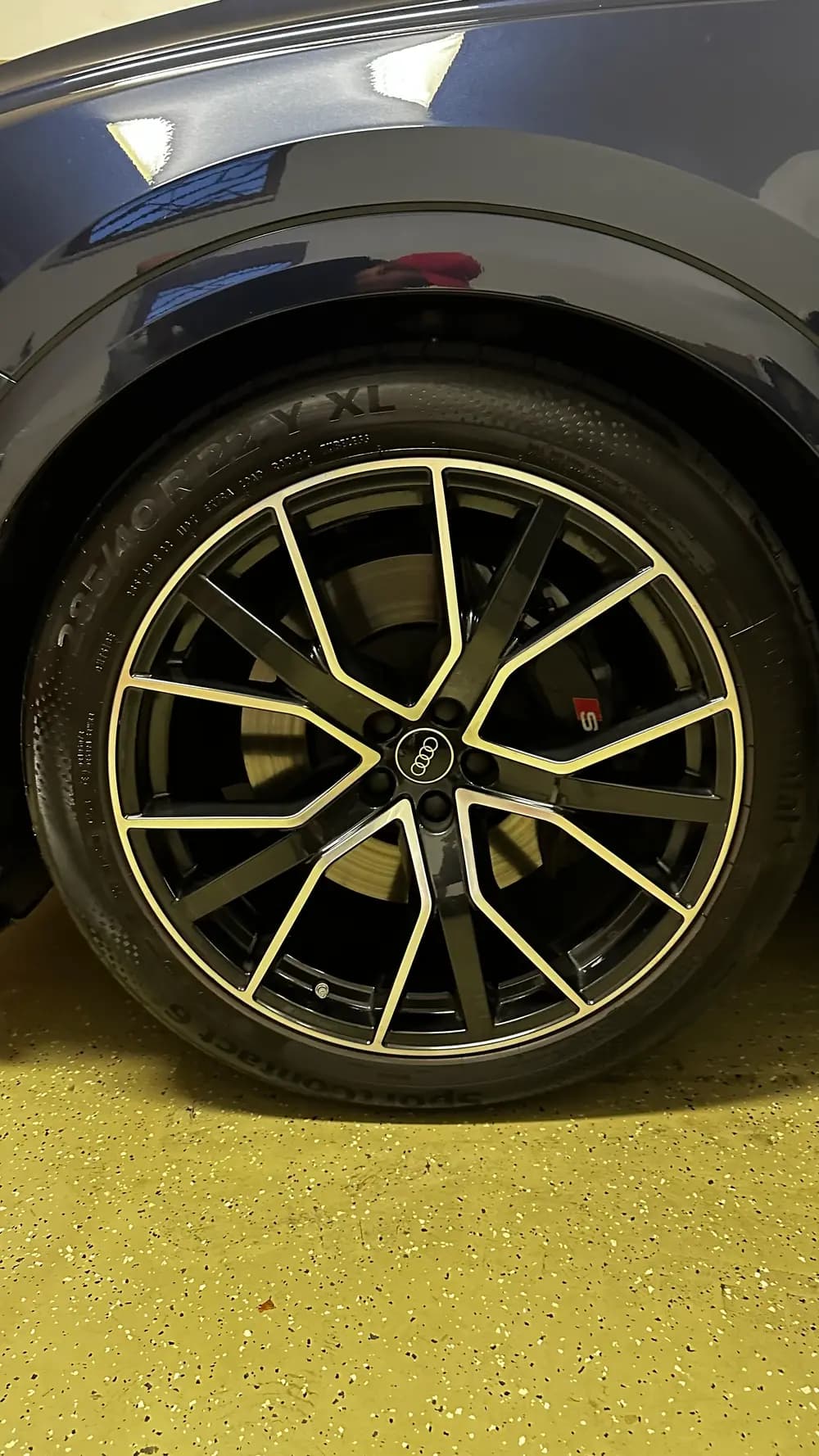 Naleštěné kolo Audi na žlutě puntíkované podlaze dílny