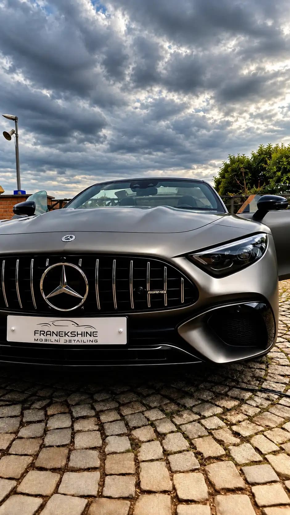 Matně šedý Mercedes-AMG SL kabriolet pod dramatickou oblohou