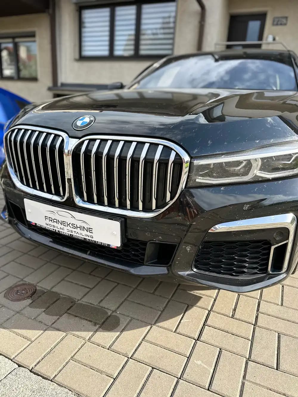 Černé BMW X7 s velkou ledvinovou maskou na zámkové dlažbě